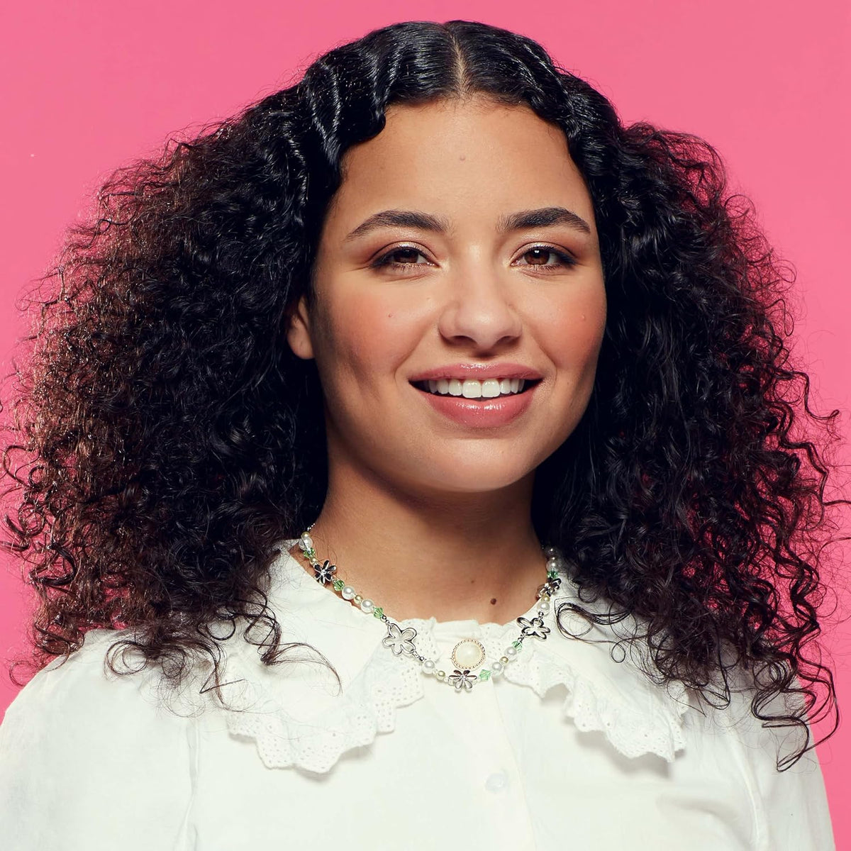 Model with dark, defined curls against a pink background