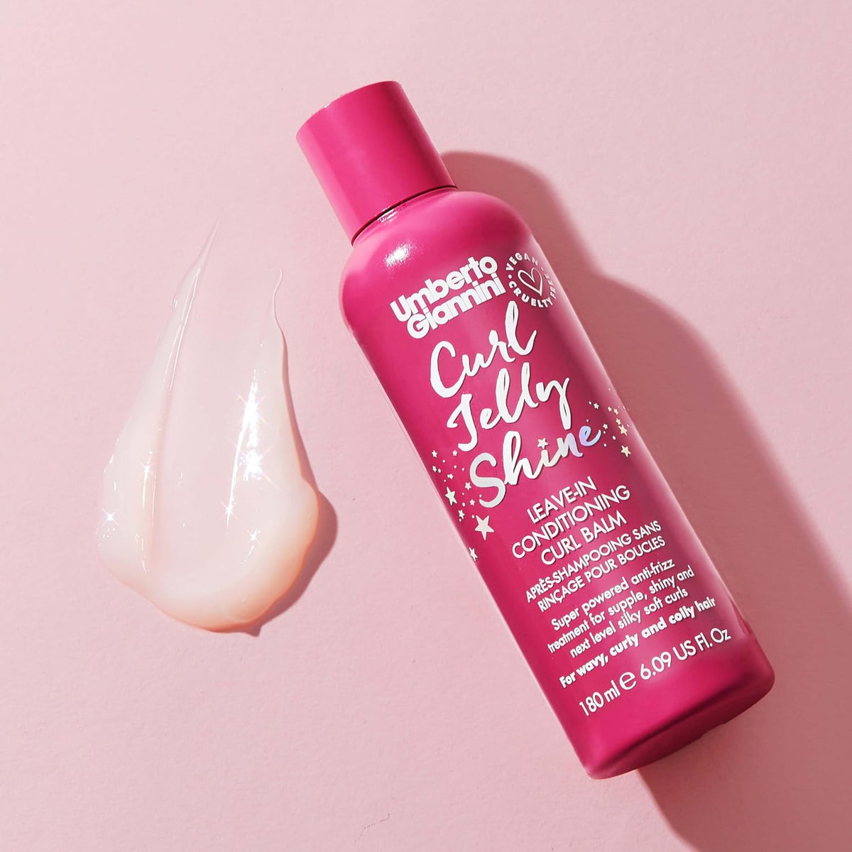 Umberto Giannini Curl Jelly Shine 180ml bottle beside a creamy balm swatch on a pink background